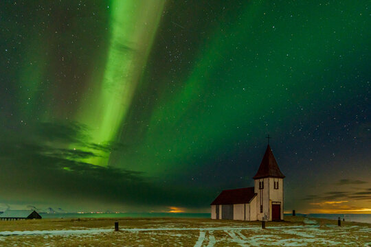 Northern lights over church and snowy plain in Iceland at night
