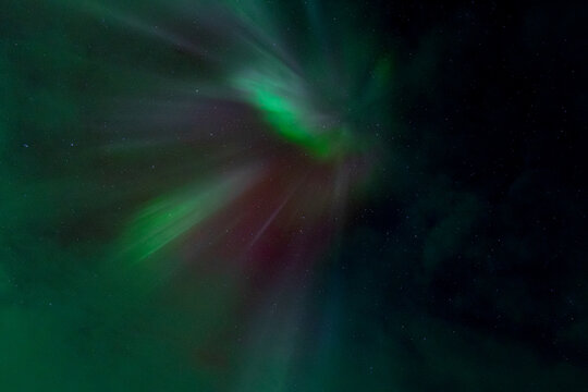Vibrant green and purple northern lights corona dancing in the starry night sky, Iceland