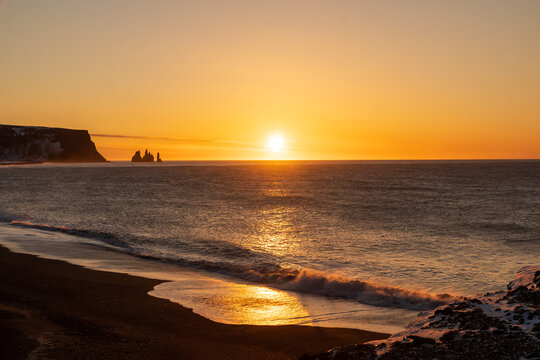 Golden sunrise over Reynisfjara black sand beach with Reynisdrangar sea stacks and ocean waves, Iceland
