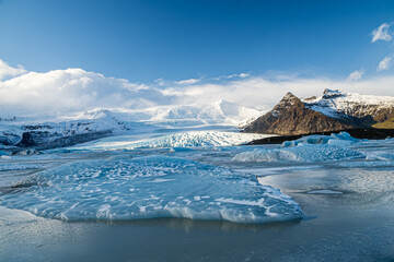 Panoramic view of a frozen glacier lagoon with floating ice sheets and massive ice cap under a blue sky, Iceland © Sandra