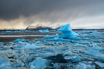 Beautiful blue icebergs floating in Jokulsarlon glacier lagoon under a dramatic stormy sky, Iceland © Sandra