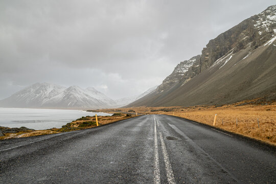 Asphalt road winding through dramatic winter landscape in Iceland