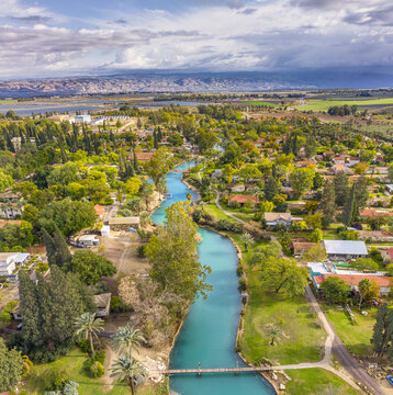 Aerial view of the Asi River flowing through the lush greenery and residential area of the kibbutz Nir David, North District, Israel.