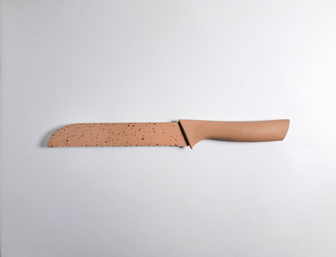 Terracotta colored bread knife on a white background. 