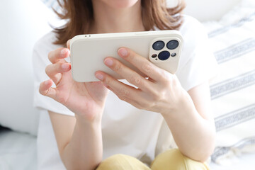 横向きでのスマートフォンを操作する女性 © webbiz