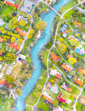 Aerial view of the Asi River flowing through the kibbutz of Nir David, surrounded by lush green lawns, trees, and residential houses in Nir David, North District, Israel.