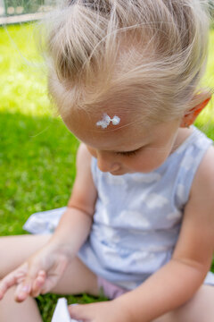 Applying soothing cream to a mosquito bite on a little girl's forehead