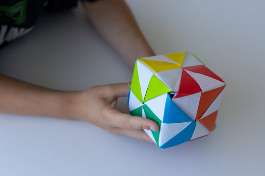 Child playing with colorful origami paper cube toy