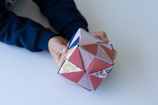Child playing with colorful origami paper cube toy