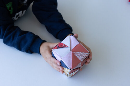 Child playing with colorful origami paper cube toy