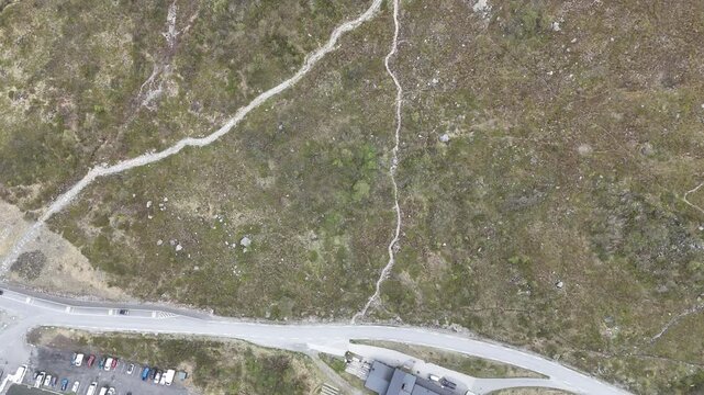 Aerial pan up of hiking trail path to top of Jotunheimen National Park mountains, Norway