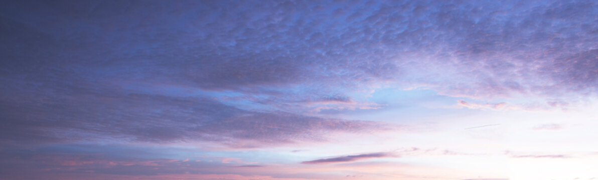 Serene sunrise sky with soft cirrocumulus clouds. Beautiful blue and pastel pink gradient background at dawn.