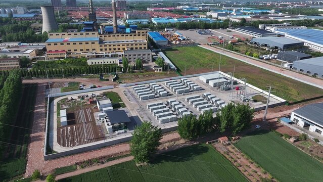 Aerial view of an energy storage power station in an industrial zone with surrounding factories and farmland
