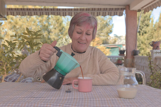 Mujer sonriente sirviendo caf&eacute; de una cafetera italiana