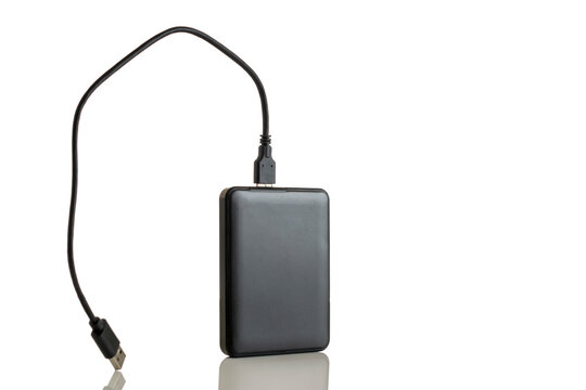 Black external hard drive disk (HDD) with USB cable connected, isolated on a white background with reflection.