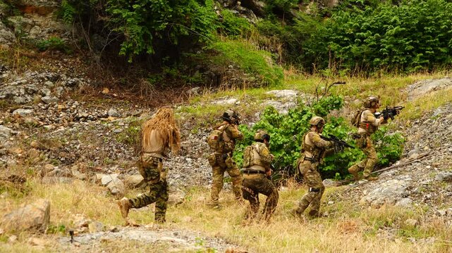 A group of soldiers in military uniforms stand holding BB guns, keeping a watchful eye on enemies during a patrol while exercising their military training, in order to play the game.