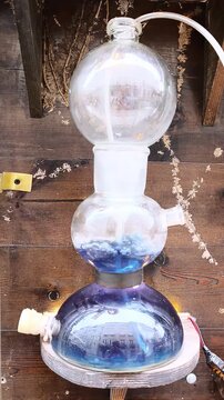 Glass laboratory apparatus with blue liquid heating on wooden wall