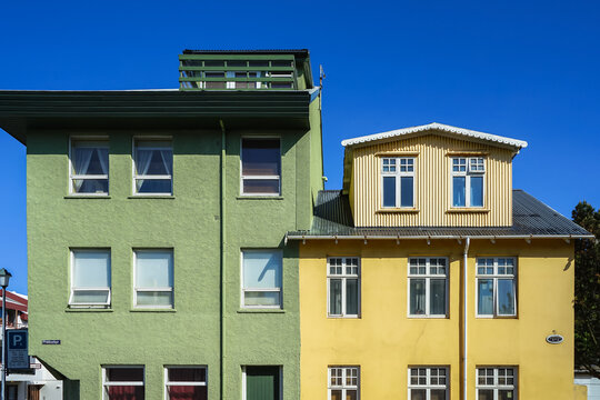 Two adjacent colorful buildings with green and yellow facades under a clear blue sky,Nordic architecture,Reykjav&iacute;k,Iceland	