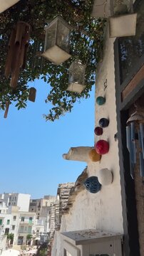 Traditional street with hanging souvenirs and blue sky in Alberobello Italy