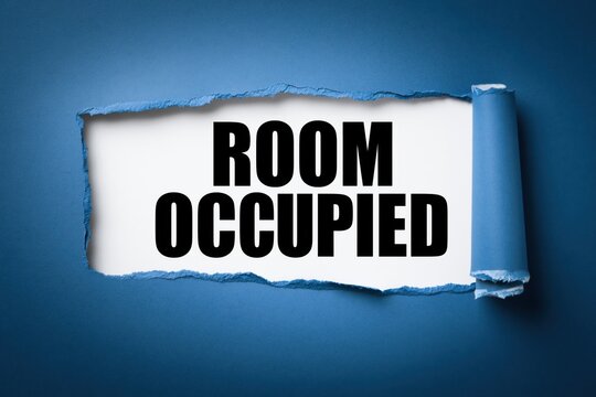 Room occupied sign shown through torn dark blue paper