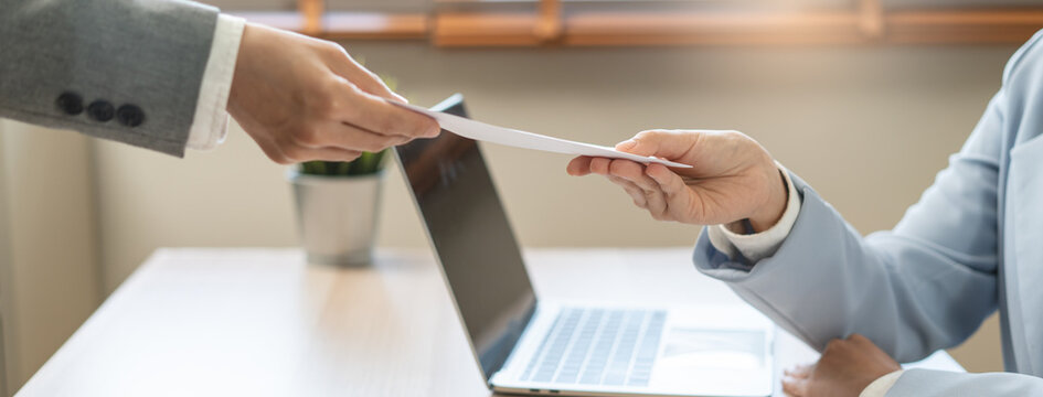 Close up of employee handing resignation letter or application to manager.