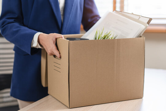 Close-up of a businessman holding a cardboard box with personal belongings after resignation.