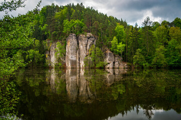 Naklejka premium Iconic sandstone cliffs reflected in the calm waters of Vezicky Pond (Vezicky rybnik in czech) in the beautiful Bohemian Paradise, Czech Republic, a famous scenic destination popular with tourists.