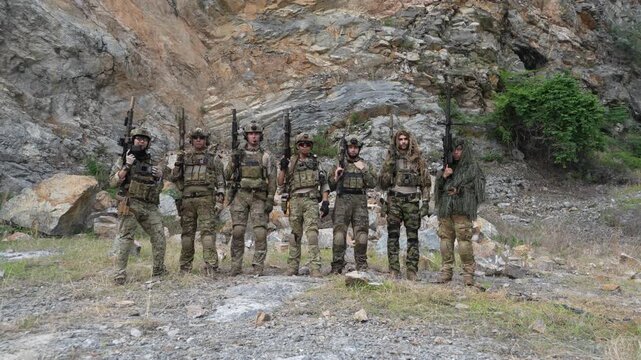 A group of Asian and Caucasian soldiers, dressed in military uniforms, trained while holding BB guns and rifles, practicing combat in a mountainous field with fire explosion effects.