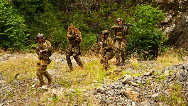 A group of soldiers in military uniforms, carrying BB guns, cautiously patrolled during a training exercise while playing a game.