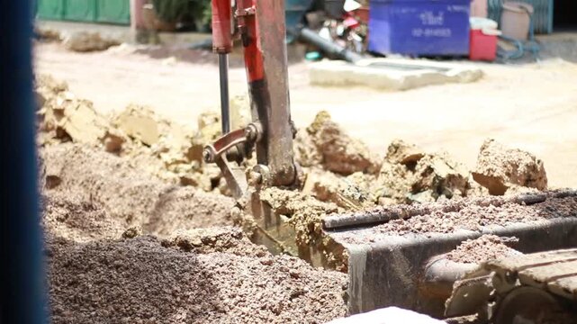 Mini excavator digging a trench for underground utility installation and pipeline repair. Heavy machinery performing excavation, infrastructure maintenance, earthmoving, and civil engineering work.