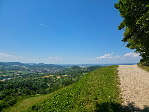germany, scenic hiking trail along forest edge overlooking dettingen an der erms valley with colorful summer landscape and endless blue sky