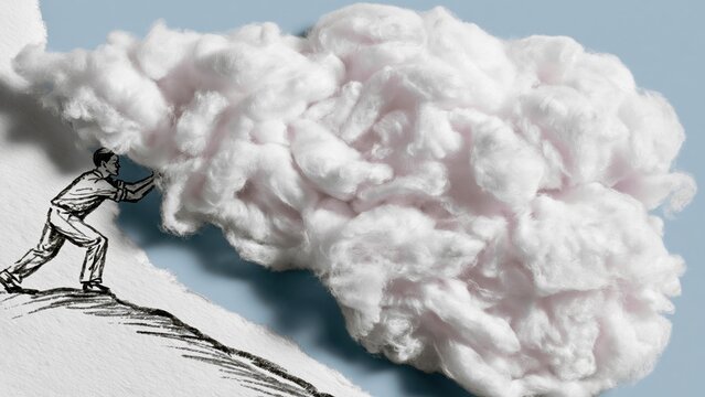 Man pushes real white cotton cloud up steep hill.