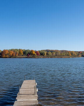 Wooden dock overlooking lake with fall foliage