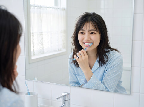 鏡の前で楽しそうに歯を磨く水玉パジャマの女性