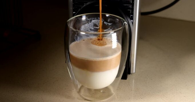 Horizontal camera angle of layered milk and espresso coffee creation process inside a clean transparent glass mug layout