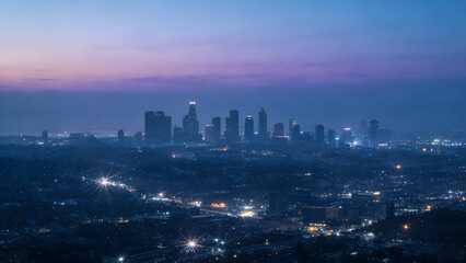 Fototapeta premium City skyline at dusk with illuminated buildings and starburst lights