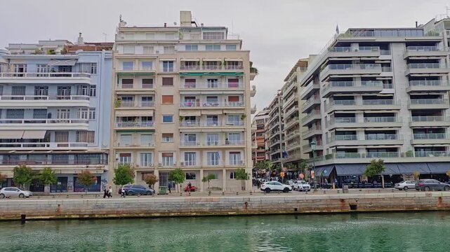 View from boat on water and buildings near water in Thessaloniki, Greece. Side view of City on coast of Thermaic Gulf 