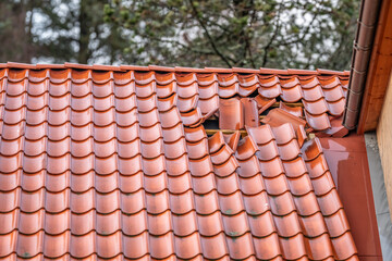 Damaged red roof tiles showing storm impact and structural wear. © Trygve