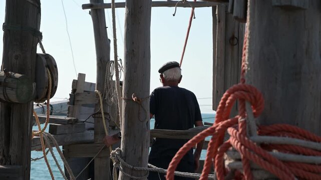 pescatori al lavoro su di un antico trabucco in legno sulle coste del gargano in puglia