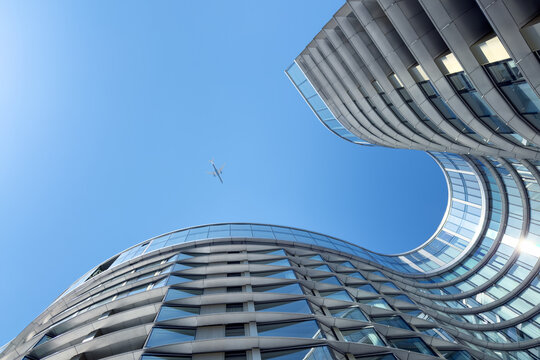 London, UK - 19 June 2026: 50 Electric Boulevard, a contemporary office space at the redeveloped Battersea Power Station site. located under the Heathrow flight path, a plane is above in the blue sky