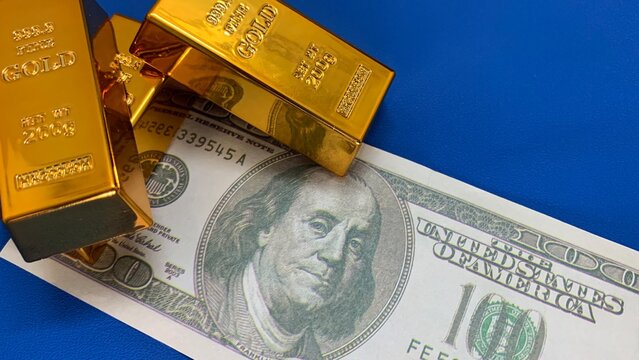 gold bars arranged over a 100 dollar bill, purpose for marketing or background