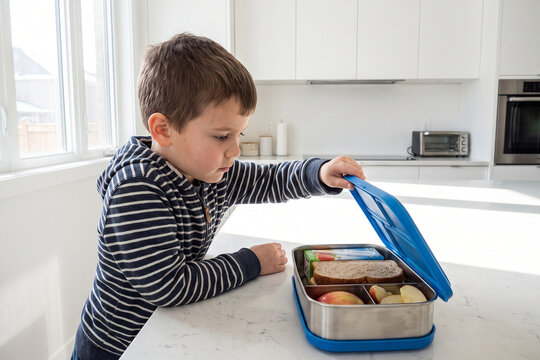 Boy Opening Lunchbox to Check Contents at Kitchen Counter
