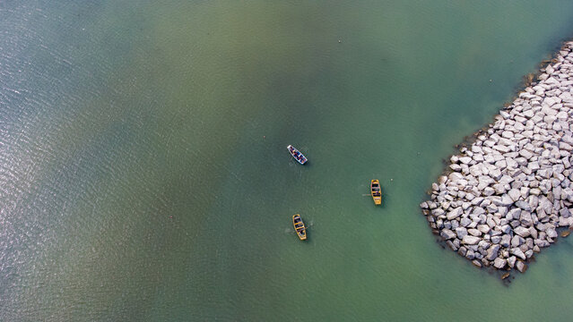 Aerial view of small boats floating in the clear turquoise water near the stone breakwater of La Punta, Callao Region, Peru.
