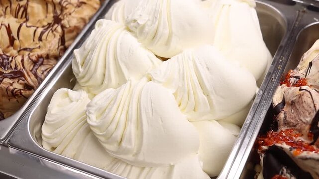 Supermarket ice cream shelf with various flavors and brands, retail food concept.
