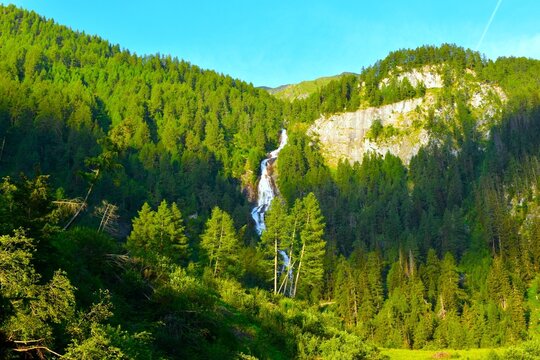 Waterfall in Umbaltal flowing down forest covered mountains in High Tauern, Tyrol, Austria