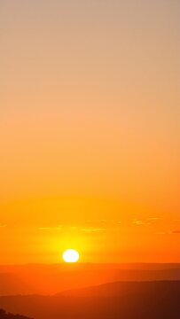 a sunset with the sun setting over the mountains