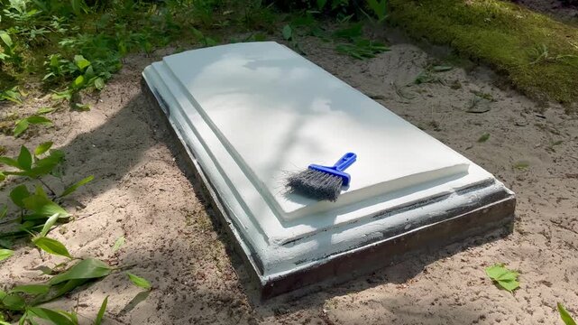 Restored concrete grave border prepared for painting after surface repair in cemetery