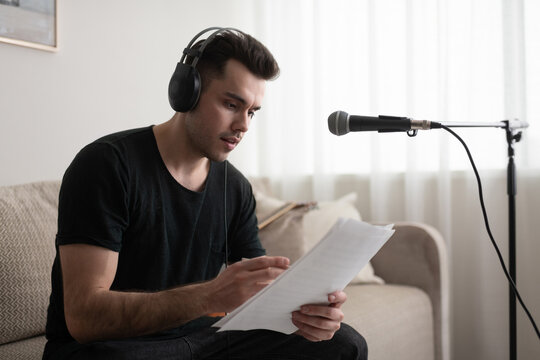 Male songwriter reading notes on couch. Man creating music at home