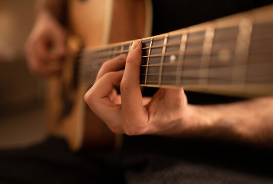 Cropped man playing and tuning guitar