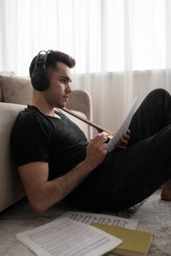 Male musician composing music on floor. Man writing song at home